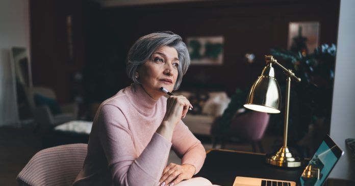 TelePsychics reading guide 2725 A woman comparing notes beside a laptop at a home desk.