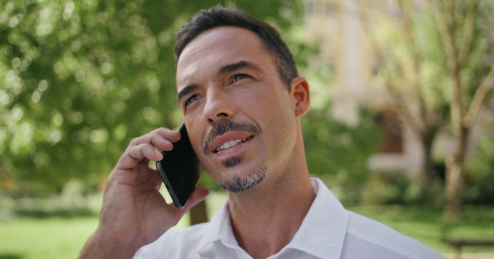 A man speaking on a mobile phone outdoors.