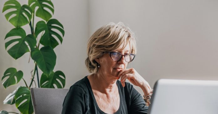 A woman reviewing information on a laptop at home.