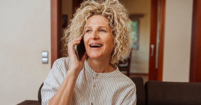 TelePsychics reading guide 2789 A curly-haired woman speaking on a phone from her sofa.