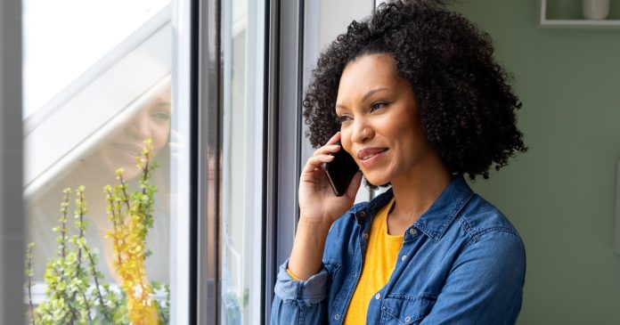 A Spiritual Connection: Meaning, Trust and Everyday Love Woman smiling during a phone conversation beside a bright window