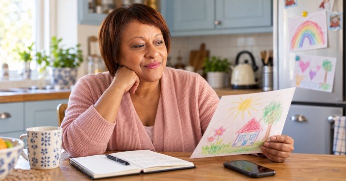 Mother considering a child's drawing at her kitchen table