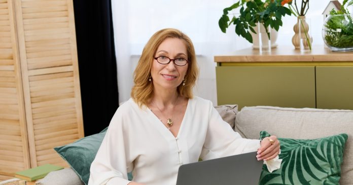 Woman using a laptop on a sofa in a bright home